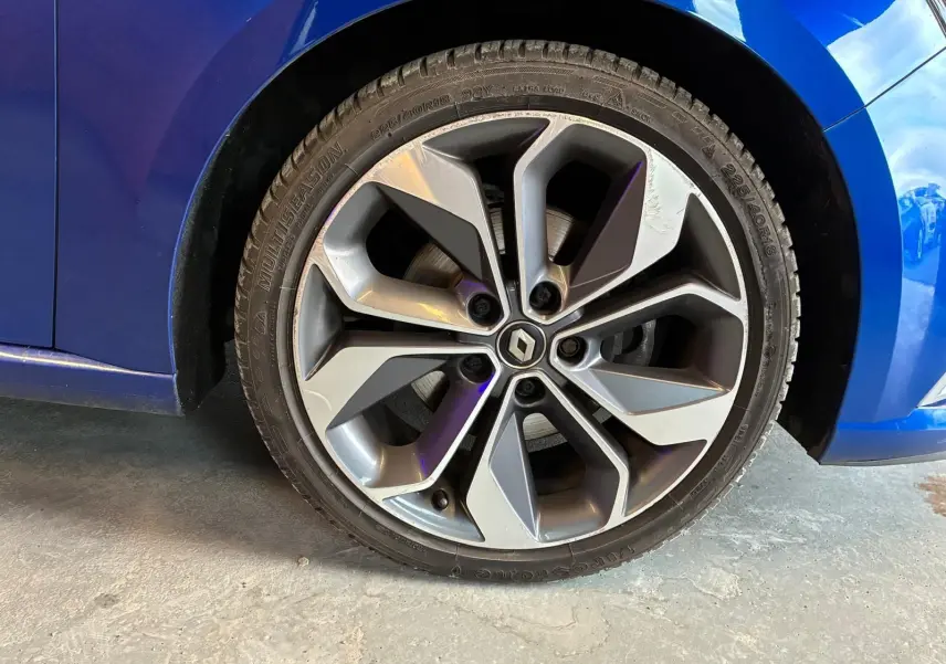 Gros plan sur la roue avant gauche d’une Renault Mégane bleu 2019 avec jante alliage gris foncé à design moderne.