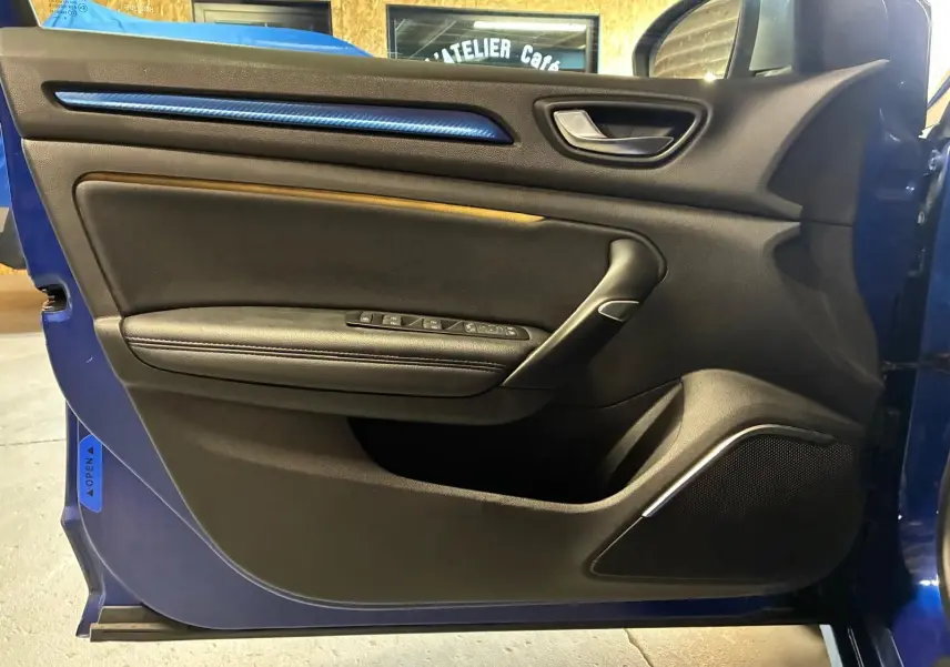 Vue intérieure de la porte avant gauche de la Renault Mégane bleu 2019, avec garniture noire et bande décorative bleue.