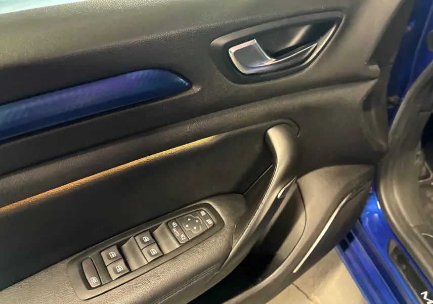 Vue rapprochée de la porte avant gauche de la Renault Mégane bleu, avec commandes électriques et insert décoratif bleu.