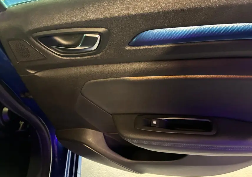 Détail de la porte avant gauche de la Renault Mégane bleu, avec poignée intérieure et insert décoratif bleu.