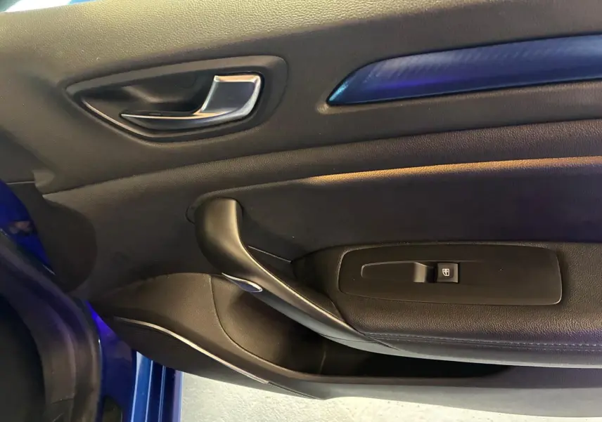 Gros plan sur la porte intérieure côté gauche de la Renault Mégane bleu, avec poignée argentée et insert bleu.