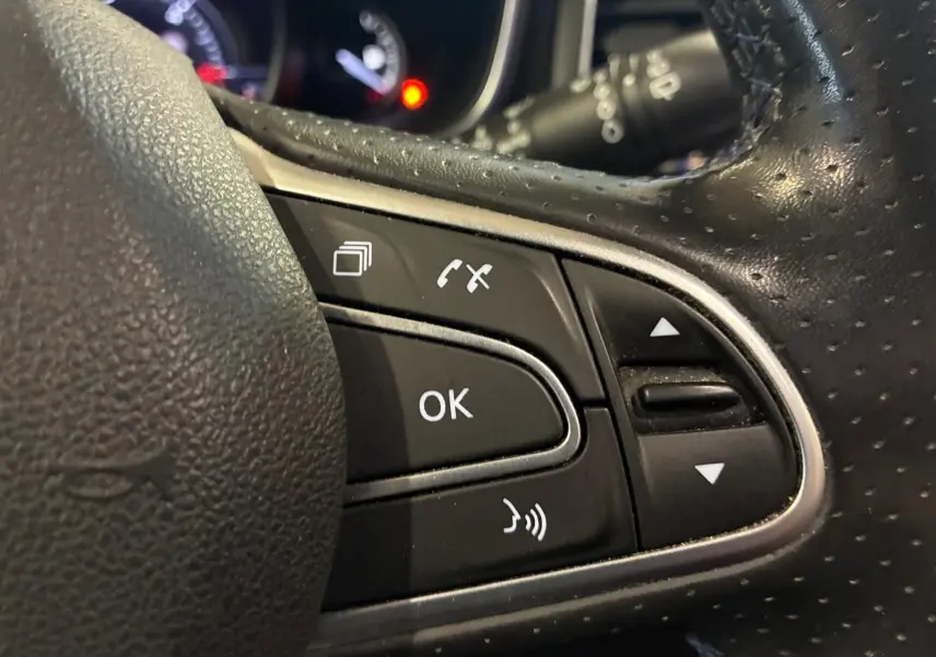 Gros plan sur les commandes multifonctions noires du volant perforé d’une Renault Mégane 1.7 BlueDCI 150 GT Line 2019.