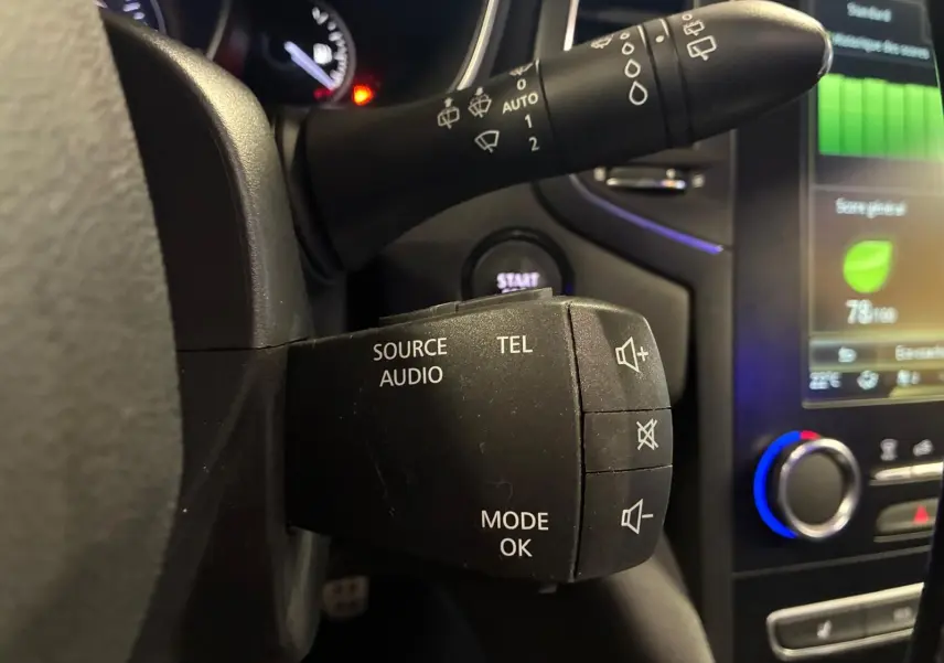 Gros plan sur la commande audio au volant de la Renault Mégane 1.7 BlueDCI 150 GT Line, intérieur noir avec écran tactile.