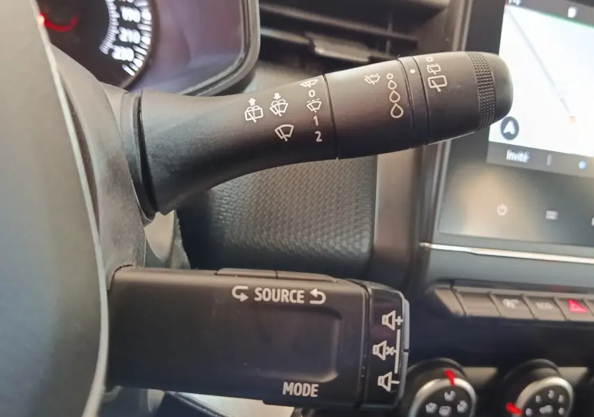 Gros plan sur les commandes au volant et le levier d'essuie-glace du tableau de bord d'une Renault Clio Business Blue dCi 100.