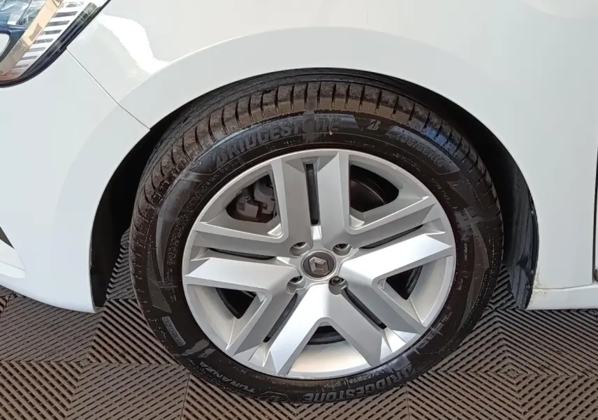 Gros plan sur la roue avant droite d’une Renault Clio blanche, avec jante alliage et pneu Bridgestone.