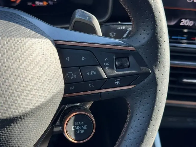 Gros plan sur le volant perforé du CUPRA Formentor 1.5 eTSI Hybrid 2025 avec boutons multifonctions et bouton start/stop éclairé.