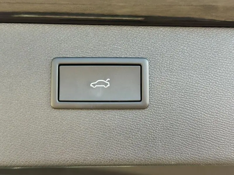 Bouton intérieur gris avec symbole blanc d'ouverture de coffre, sur panneau texturé du CUPRA Formentor 1.5 eTSI Hybrid 2025.