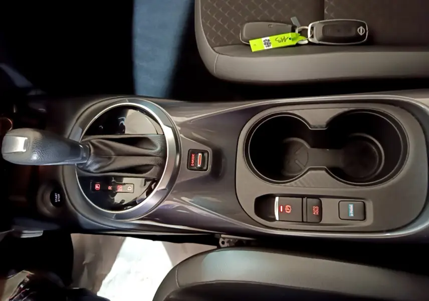 Vue plongeante sur la console centrale du Nissan Juke Hybrid 143 Business+ 2023 avec levier de vitesses et porte-gobelets.