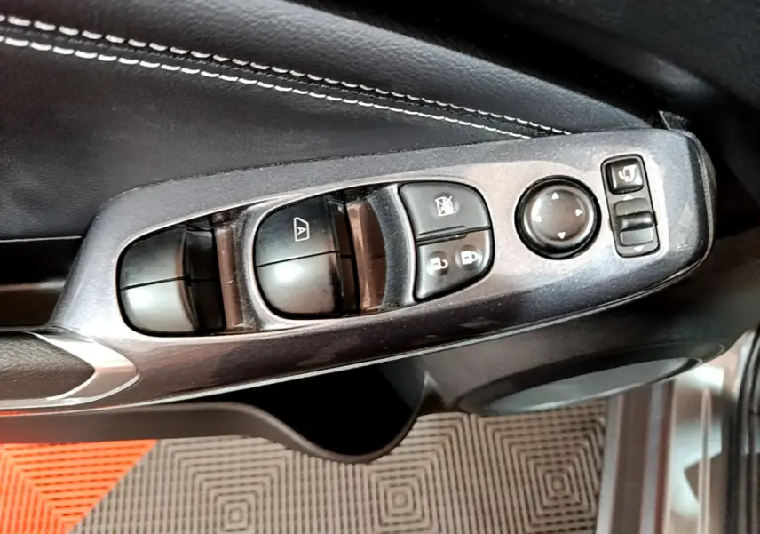 Commandes des vitres et rétroviseurs côté conducteur du Nissan Juke Hybrid 2023 gris foncé, intérieur en cuir noir.