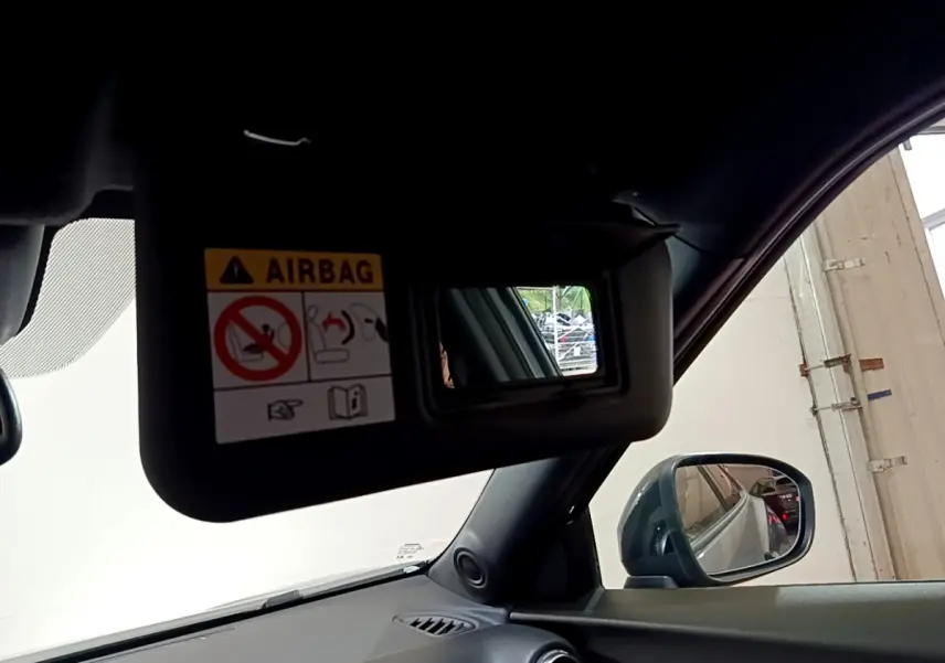 Détail du pare-soleil côté conducteur avec miroir et avertissement airbag dans le Nissan Juke Hybrid gris foncé 2023