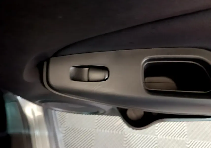 Détail de la poignée intérieure de porte côté conducteur du Nissan Juke Hybrid 143 Business+ gris foncé 2023.