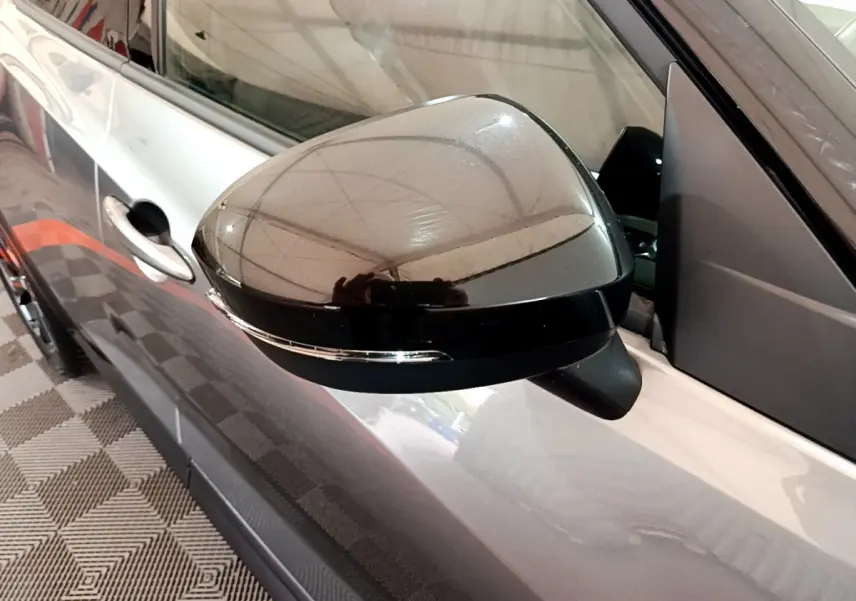 Rétroviseur gauche noir brillant du Nissan Juke Hybrid gris foncé, avec clignotant intégré, vue en gros plan.