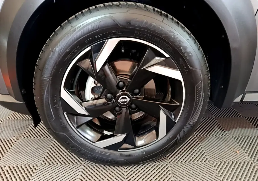 Gros plan sur la roue avant droite du Nissan Juke Hybrid 143 Business+ gris foncé avec jante noire et argentée.