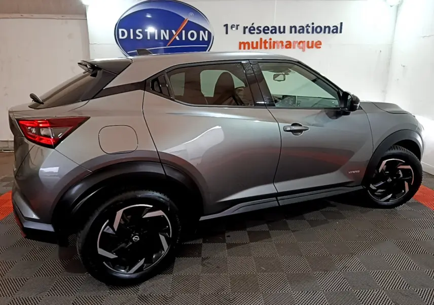 Nissan Juke Hybrid gris foncé vue de profil côté gauche, avec jantes noires et toit contrasté blanc.