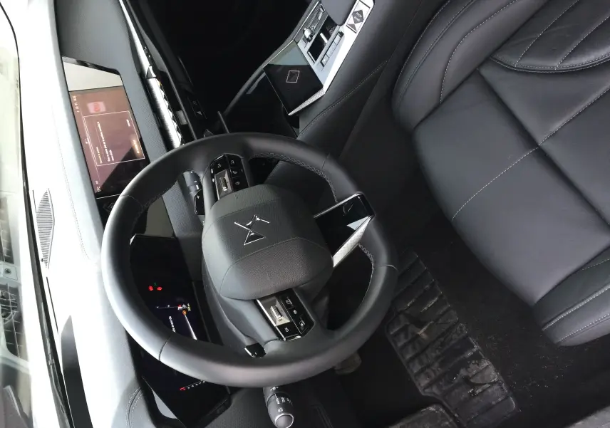 Vue plongeante sur l'intérieur noir cuir du DS4 2024, avec volant multifonction et tableau de bord numérique.
