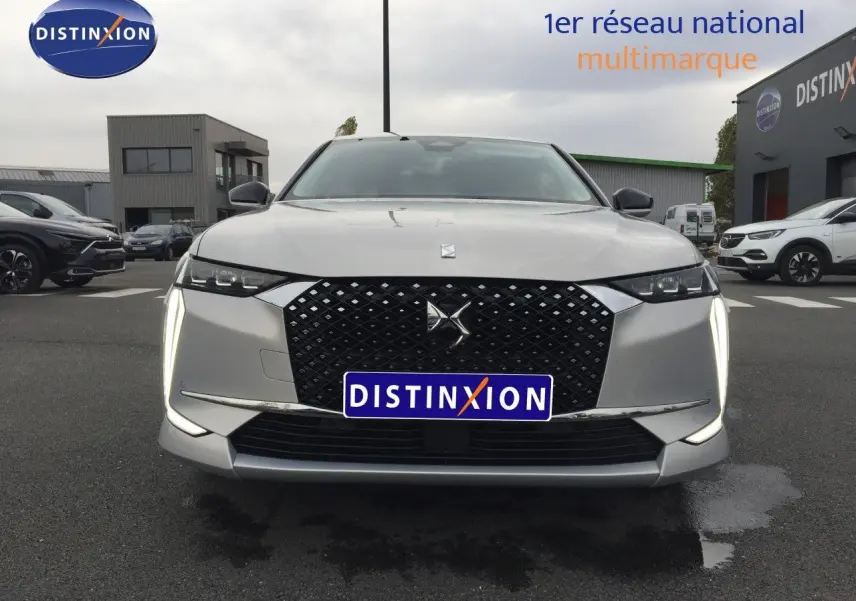 Vue frontale d'une DS4 2024 Eph Crystal avec calandre noire et feux LED verticaux allumés sur parking.