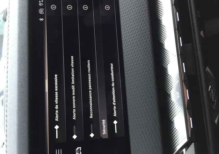 Vue rapprochée de l’écran tactile intérieur du DS4 2024 affichant les alertes de sécurité sur un tableau de bord texturé gris.
