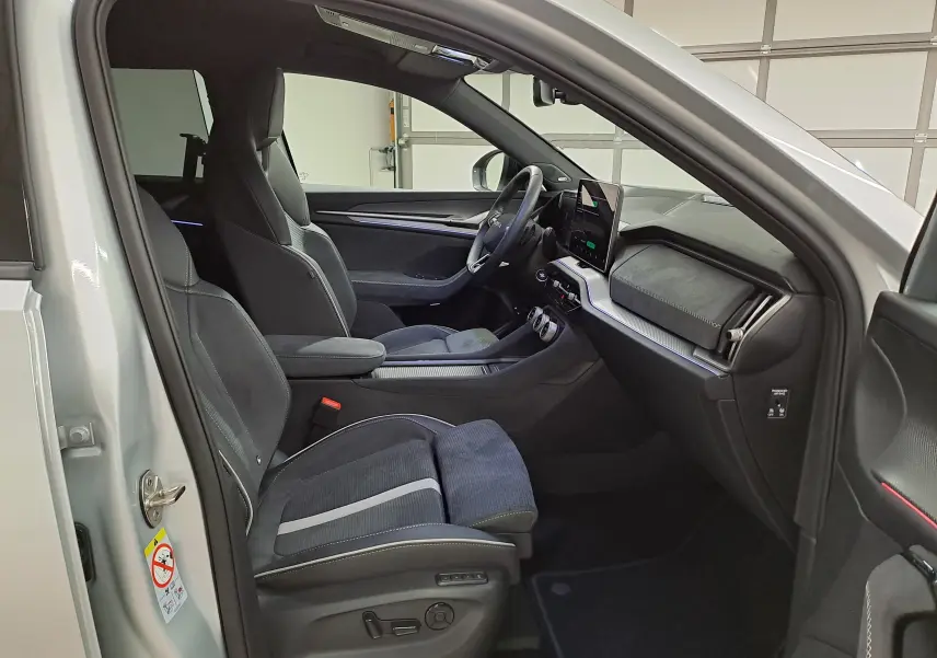 Intérieur côté conducteur du Skoda Kodiaq gris argent 2025, sièges sport noirs avec surpiqûres et tableau de bord moderne.