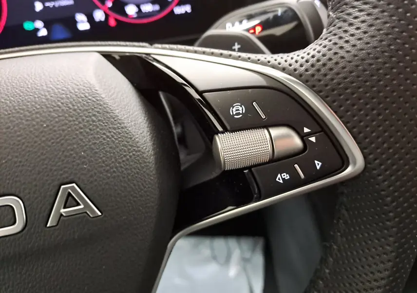 Gros plan sur les commandes multifonctions à droite du volant perforé d’un Skoda Kodiaq gris argent 2025.