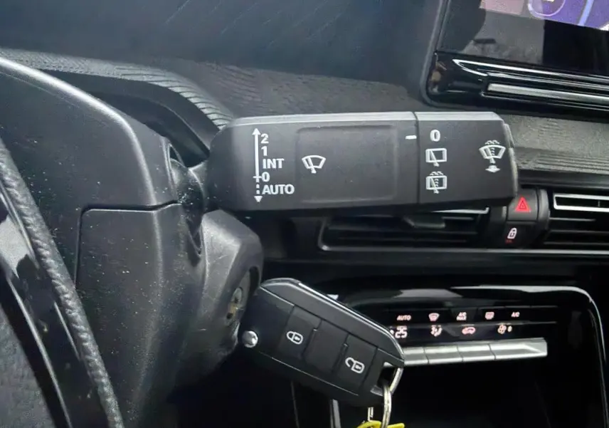 Gros plan sur la commande d’essuie-glace et la clé insérée dans le contacteur d’une Citroën C3 gris, intérieur noir.