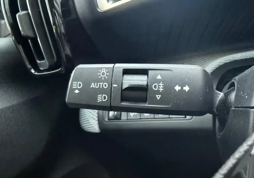 Gros plan sur la commande de feux automatique et clignotants à gauche du volant d'une Citroën C3 gris 2025.