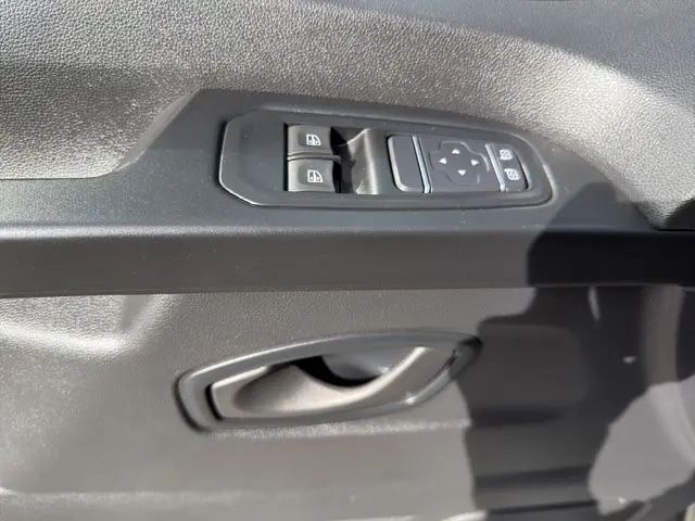 Gros plan sur la commande des vitres électriques et la poignée intérieure côté conducteur du Renault Trafic Combi gris platine.