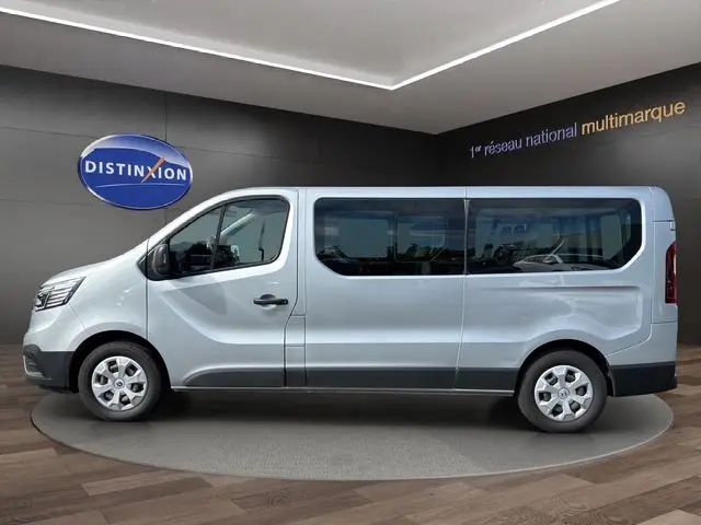Vue de profil côté gauche du Renault Trafic Combi gris platine 2022, version 9 places avec grandes fenêtres latérales.