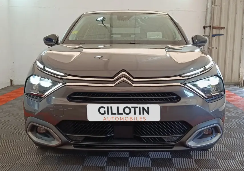 Vue frontale d'une Citroën C4 gris foncé 2022 avec phares LED allumés et calandre distinctive double chevron.
