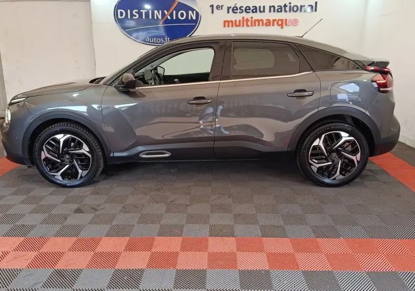 Vue de profil côté gauche d'une Citroën C4 gris foncé 2022 avec jantes noires et toit noir brillant.