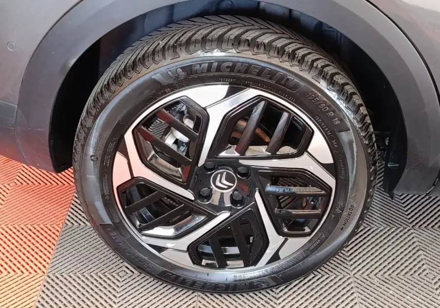 Gros plan sur la roue avant droite gris foncé d'une Citroën C4 2022 avec jante alliage noire et argentée.