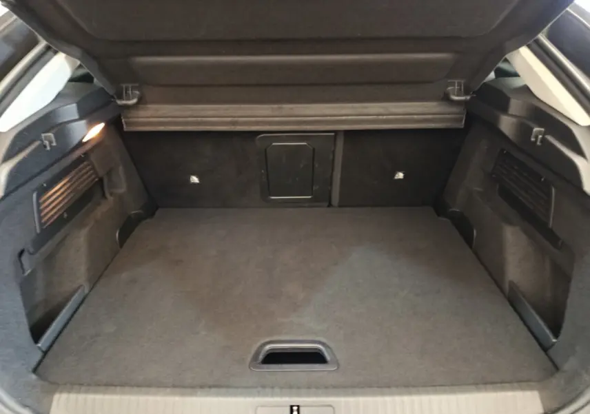Coffre ouvert vu de face d’une Citroën C4 2022 gris foncé, espace de chargement propre et bien éclairé.