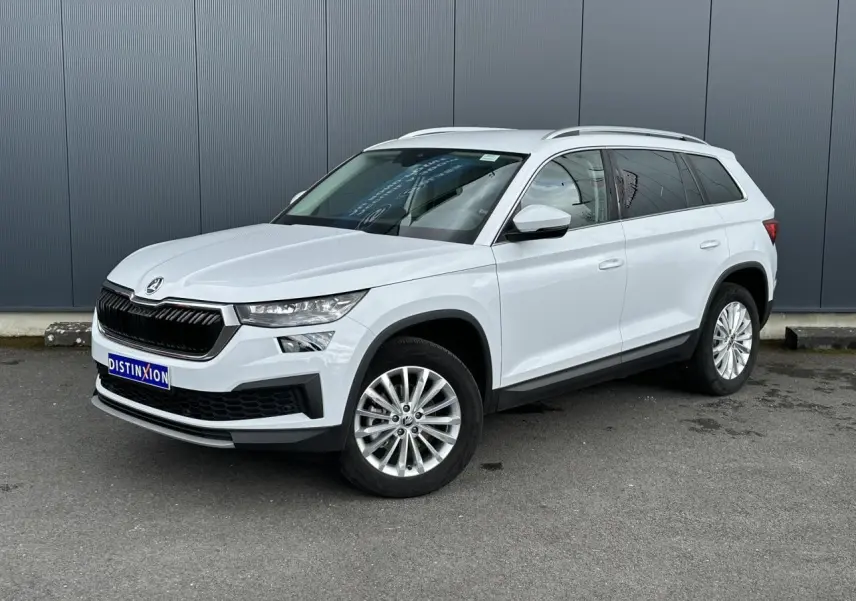 Vue 3/4 avant droit d'un Skoda Kodiaq blanc glacier avec jantes alliage 18 pouces sur fond urbain.
