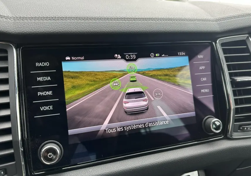 Écran central du Skoda Kodiaq 2024 montrant l'interface d'assistance à la conduite avec vue routière virtuelle.