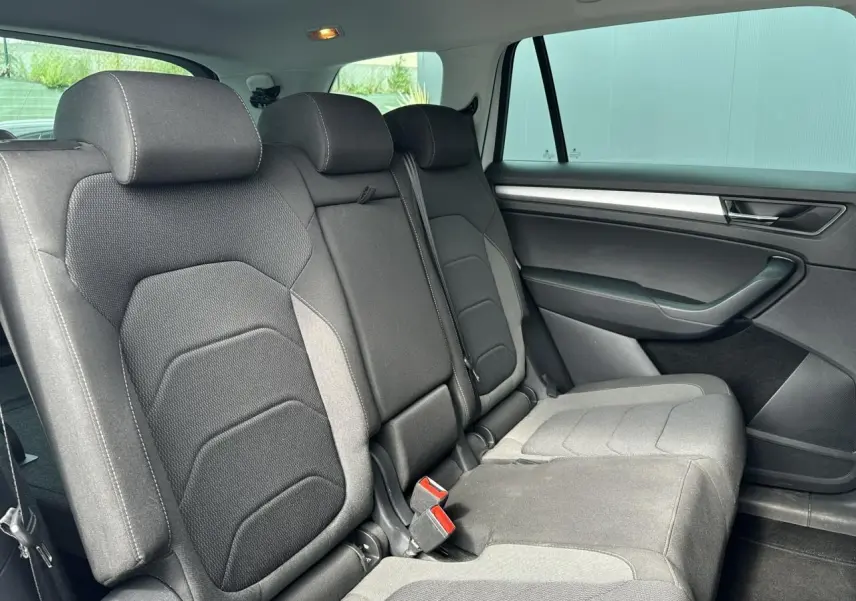 Vue intérieure côté droit des sièges arrière noirs du Skoda Kodiaq blanc Glacier 2024 avec habillage de porte sombre.