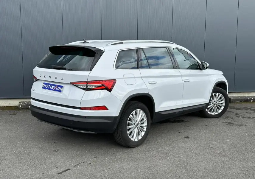 Vue 3/4 arrière droite d'un Skoda Kodiaq blanc Glacier avec jantes alliage 18 pouces et feux arrière LED.