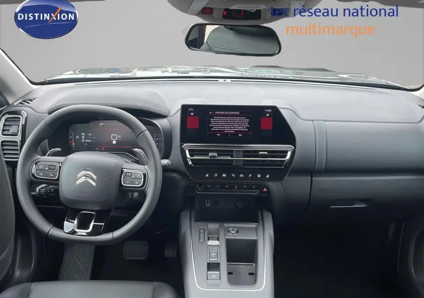Vue intérieure avant du Citroën C5 Aircross 2025, tableau de bord gris avec écran tactile central et volant multifonction.