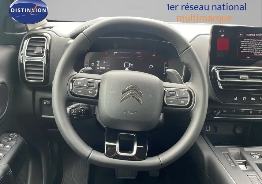 Vue intérieure centrée sur le volant noir du Citroën C5 Aircross 2025 avec tableau de bord digital et écran tactile.