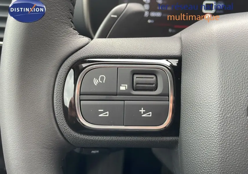 Gros plan sur les commandes gauche du volant du Citroën C5 Aircross 2025, cuir noir et boutons de réglage audio.