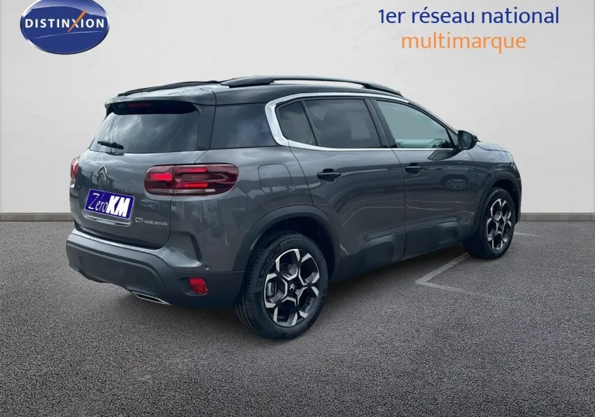 Vue 3/4 arrière droite d'un Citroën C5 Aircross gris platinium avec toit noir et jantes distinctives biton.