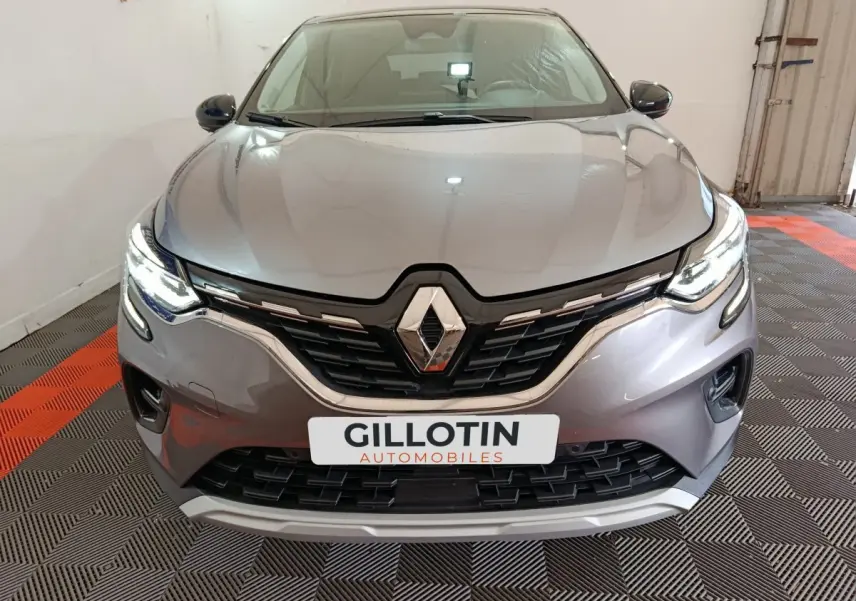 Vue frontale d'un Renault Captur gris foncé 2024 avec phares LED allumés et calandre noire brillante.