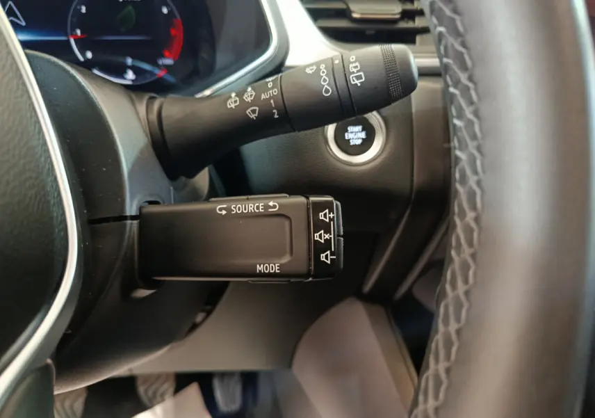 Gros plan sur la commande multifonctions côté gauche du volant du Renault Captur gris foncé avec bouton démarrage visible.