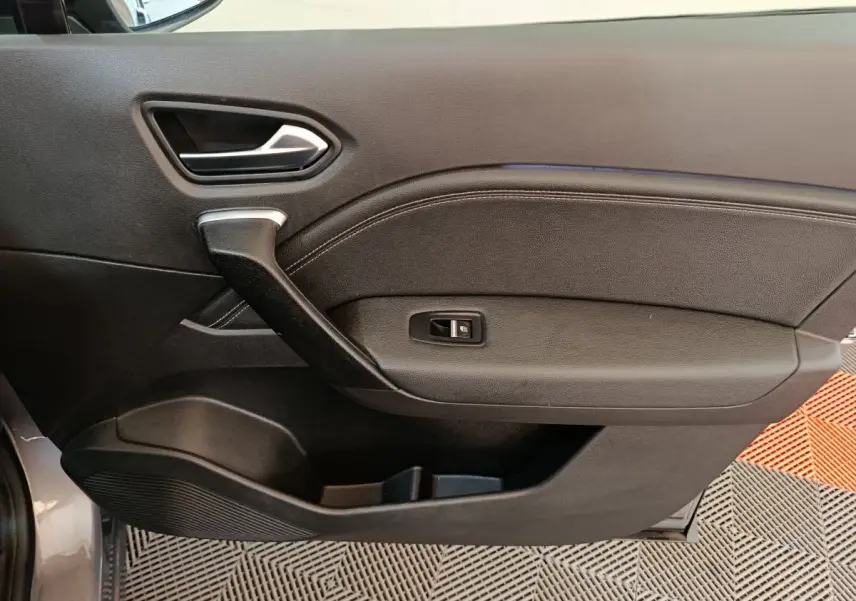 Vue rapprochée de la porte côté gauche gris foncé du Renault Captur 2024 avec poignée et commande de vitre électrique.