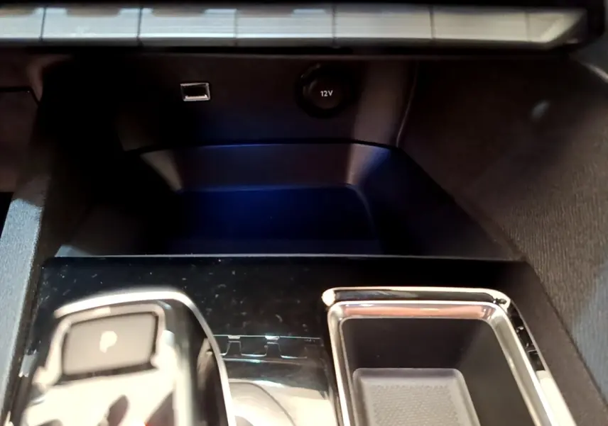 Gros plan sur la console centrale noire brillante du Peugeot 3008 avec levier de vitesses automatique et prise 12V.