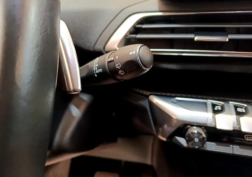 Détail intérieur du volant et commande d’essuie-glace du Peugeot 3008 2022, finition Allure, en gris foncé.