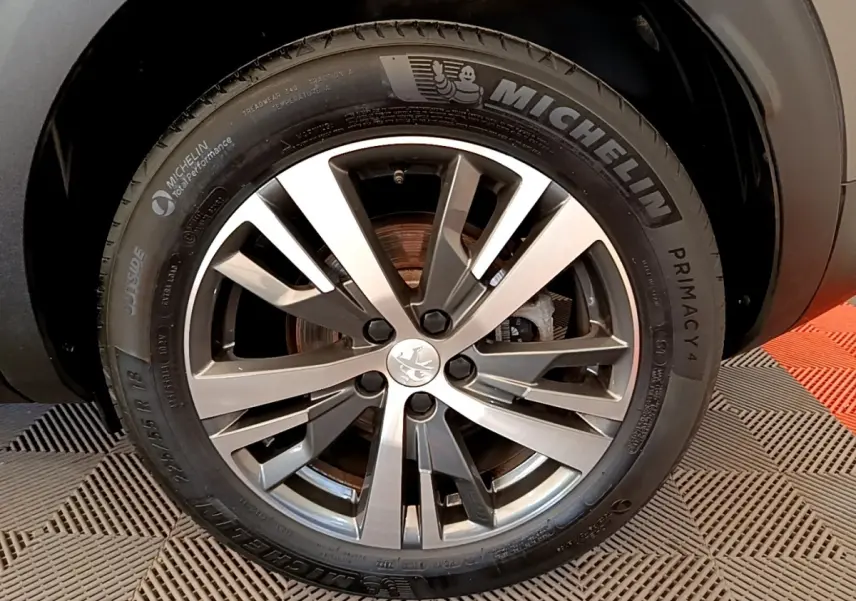 Gros plan sur la roue avant droite d’un Peugeot 3008 gris foncé, jante alliage et pneu Michelin Primacy 4.