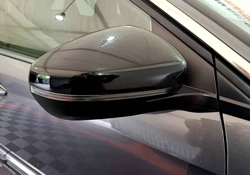 Rétroviseur côté gauche noir brillant sur Peugeot 3008 gris foncé, vue rapprochée en intérieur.
