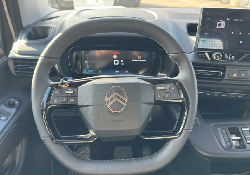 Vue intérieure centrée sur le volant noir du Citroën Berlingo 2025 avec tableau de bord digital et écran tactile.
