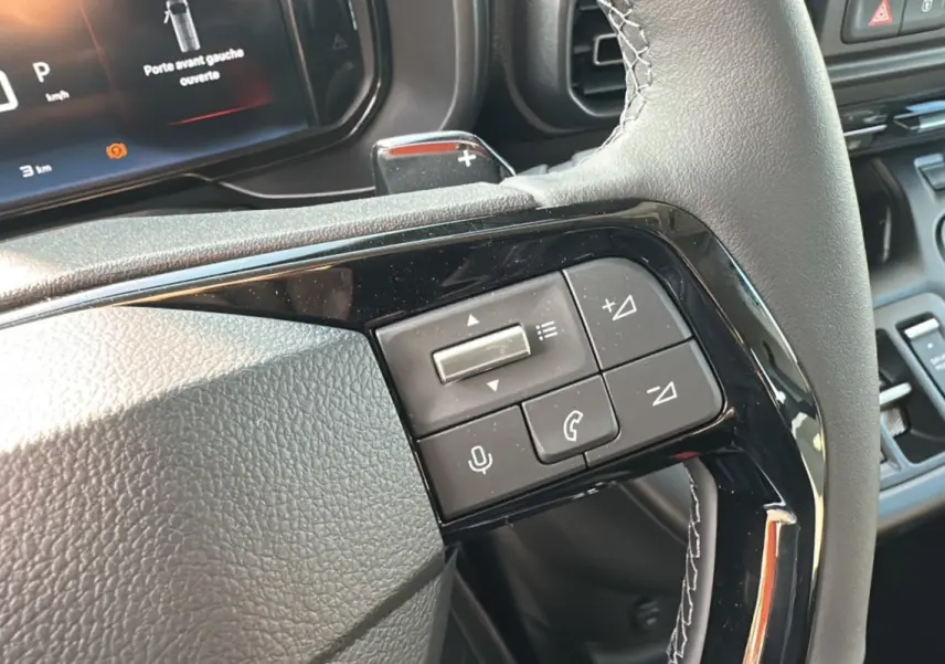 Vue rapprochée des commandes au volant du Citroën Berlingo 2025, finition BlueHDi 130 EAT8, avec tableau de bord numérique.