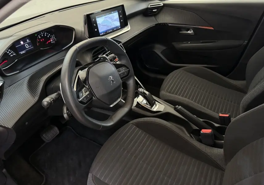 Intérieur noir de la Peugeot 208 PureTech 100, vue côté conducteur, volant cuir et écran tactile central visible.