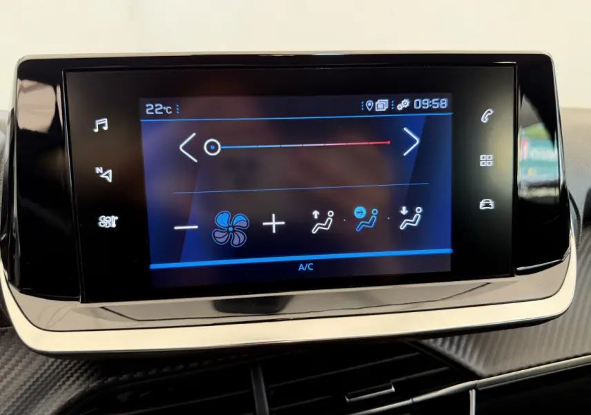 Écran tactile central de la climatisation sur tableau de bord d'une Peugeot 208 noire, vue rapprochée.